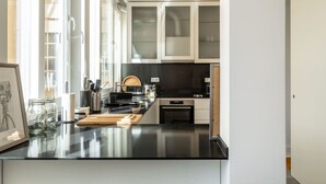 Une cuisine moderne dotée d’un plan de travail noir, d’appareils électroménagers en acier inoxydable et d’une grande fenêtre qui laisse entrer la lumière naturelle.