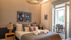 Une chambre à coucher avec un lit, des tables de chevet, un lustre et des œuvres d’art accrochées au mur.