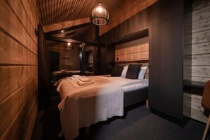 Une pièce aux murs lambrissés, comprenant un lit, un miroir et un luminaire suspendu.