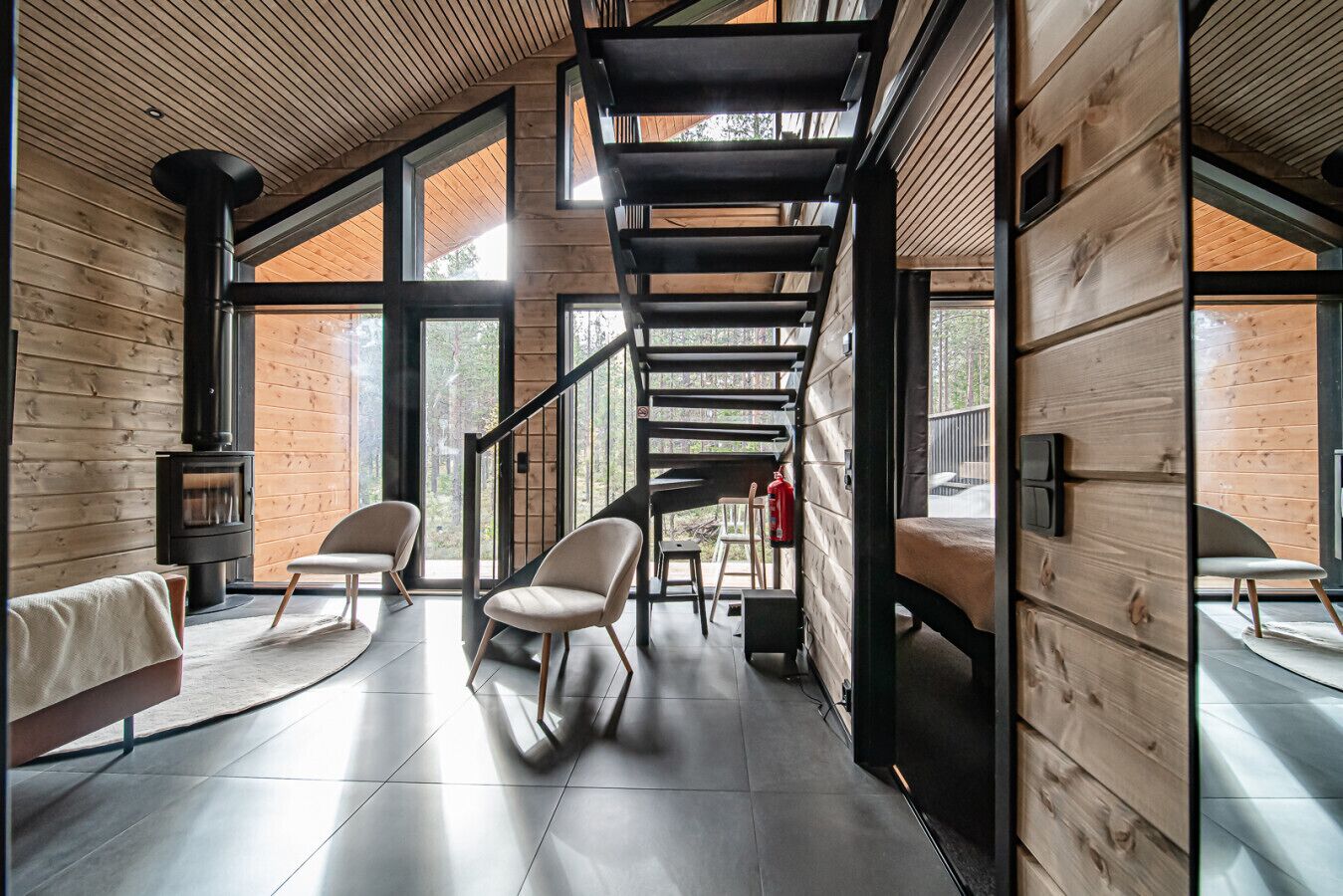 Interior de una cabaña moderna de troncos con una escalera central, chimenea y una zona de estar acogedora.