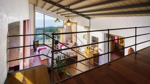 Amplia sala de estar con escalera de madera, ventanas grandes y vistas al exterior.