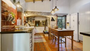 Una cocina con una mesa de madera, luces colgantes y un suelo de baldosas.
