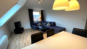 A modern loft-style apartment with a dining area, a sofa set, and a view of the city. - Tanne 16 (Braunlage)