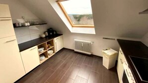 A compact kitchen with a skylight, a radiator, and a stove. - Tanne 16 (Braunlage)