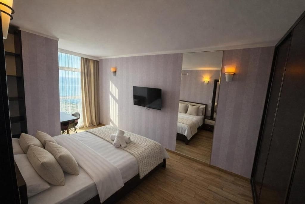 A hotel room with a large bed, a television, and a view of the city.