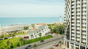 A high-rise hotel with a view of the sea and a prominent clock tower in the background. - Batumi Royal Apartments (Batumi)