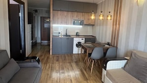 A compact living space with a kitchenette, a dining area, and a sofa. - Batumi Royal Apartments (Batumi)