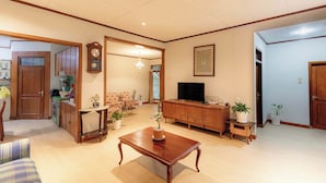A spacious living room with a wooden coffee table, a television, and various potted plants. - Imah Budi Luhur  (Bandung)