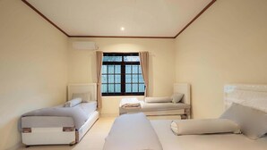 A room with two beds, a window with curtains, and an air conditioning unit on the wall. - Imah Budi Luhur  (Bandung)