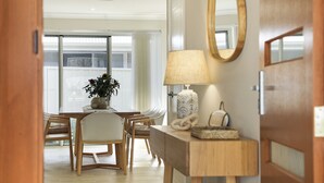 A dining area with a wooden table and chairs, a vase with flowers, a lamp, and a mirror on the wall. - Coastal Drift – your Jervis Bay escape starts here (Callala Bay)