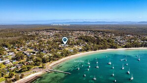 An aerial view of Callala Bay Shops with a coastal area, houses, and boats in Jervis Bay. - Coastal Drift – your Jervis Bay escape starts here (Callala Bay)