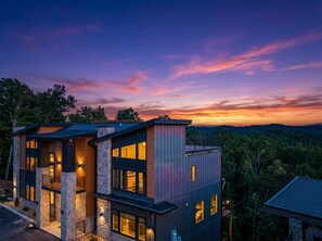 A modern multi-story building with a stone facade, large windows, and a balcony.