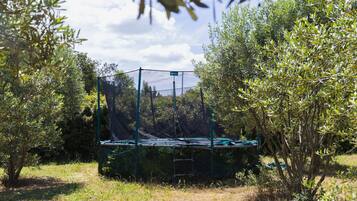 Un trampolín en un jardín rodeado de olivos.