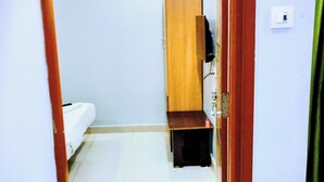 A narrow hallway with a white toilet, a wooden cabinet, and a red door. - THE ROYAL STAY IN (Hyderabad)