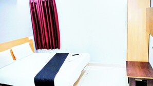 A hotel room with a bed, a desk, and a wardrobe. - THE ROYAL STAY IN (Hyderabad)