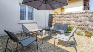 Un espacio al aire libre con una mesa, dos sillas y una sombrilla grande.