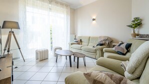 Un salón con sofá, mesa de centro, lámpara y planta en maceta.
