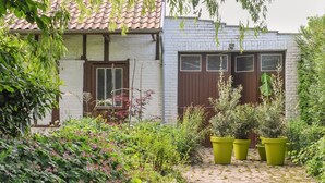 A cobblestone pathway leading to a white building with a red-tiled roof and brown doors.