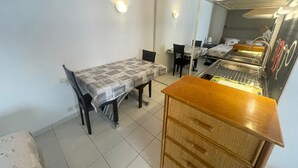 A dining area with a table and chairs, a kitchen area with a sink and stove, and a mirror reflecting the room.