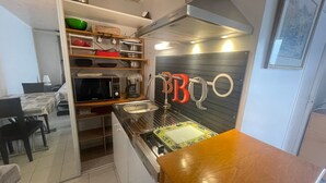 A compact kitchen with a microwave, coffee maker, and a sink. There is a dining area with a table and chairs.