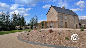 Een stenen huis met een overdekte patio en een grindtuin.