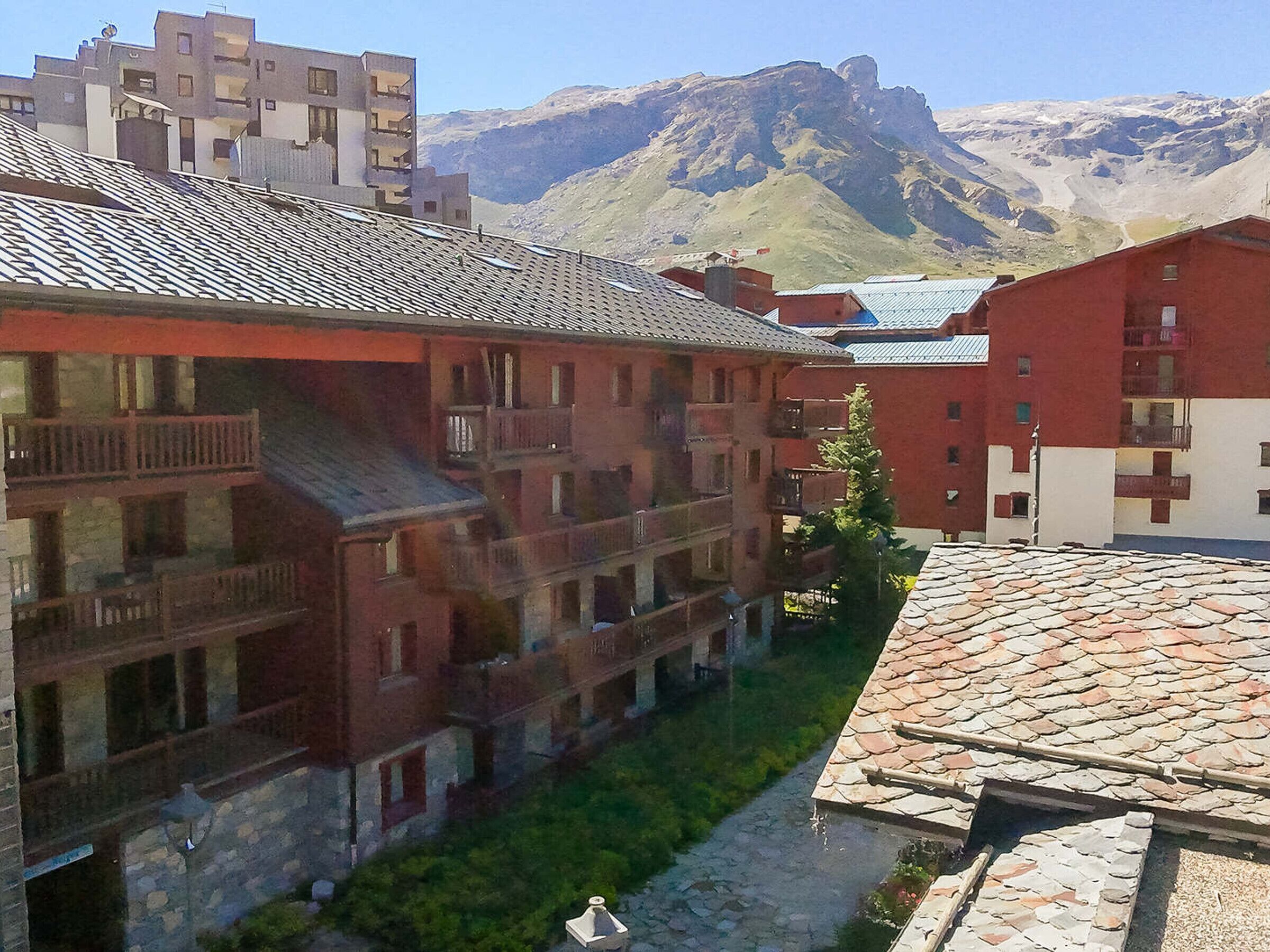 Un immeuble à plusieurs étages doté de balcons, d’une cour intérieure et surplombant un paysage montagneux.