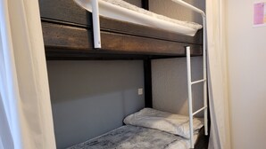 A bunk bed with a ladder, a single bed below, and a white curtain partially visible. - Spacious Studio in Pra-Loup 1600 | 4 pers, balcony, WIFI (Pra-Loup)