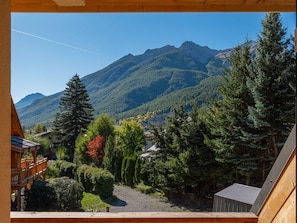 Vista de la montaña desde una cabaña de madera con cielo despejado.