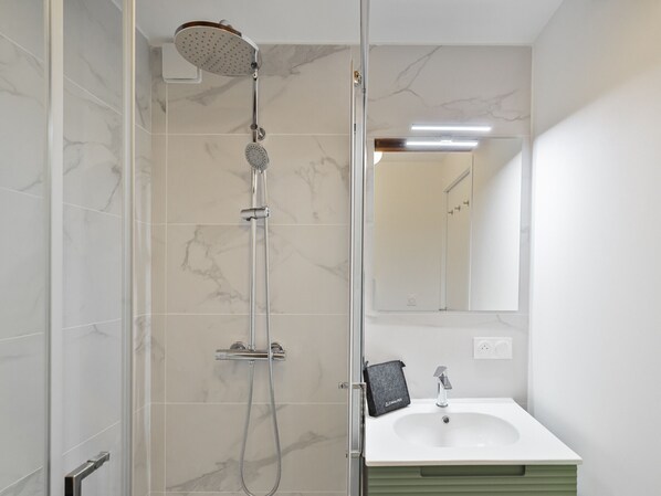 A modern bathroom with a glass shower enclosure, a white sink, and a mirror above the sink. - Family apartment 4 adults + 4 children, near village, parking (Le Monêtier-les-Bains)