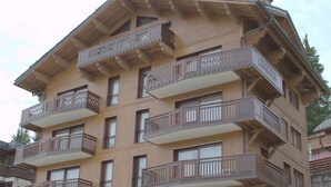 A multi-story wooden building with balconies and large windows.