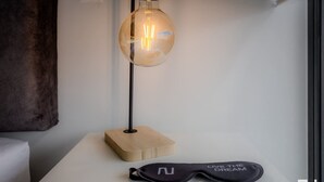 Une chambre moderne avec une table ronde, une lampe en bois et une paire de masques de sommeil noirs posés sur la table.