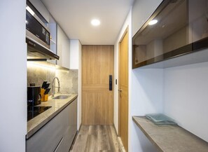 A narrow kitchen with a wooden door, a built-in oven, and a countertop with a sink.
