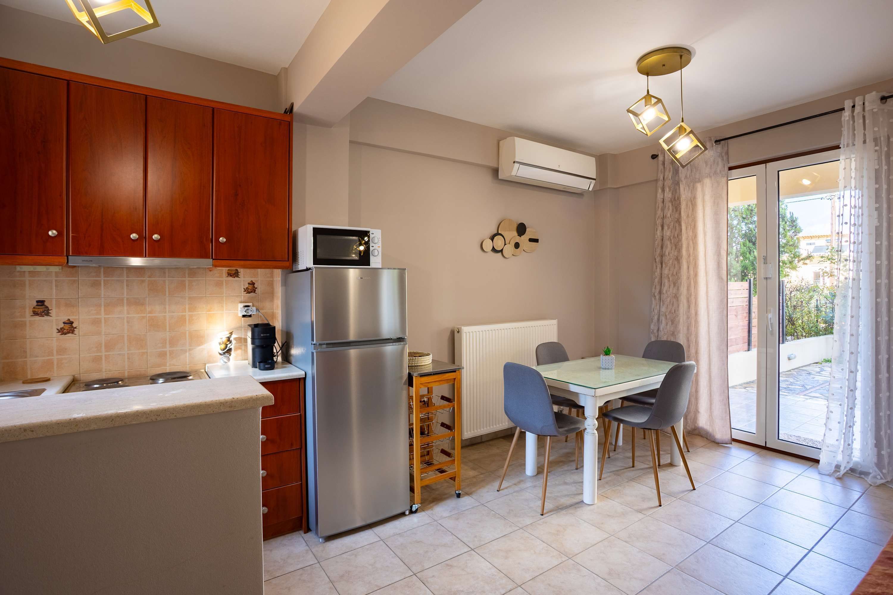 Una cocina con armarios de madera, un refrigerador de acero inoxidable, un microondas y una mesa de comedor con sillas.