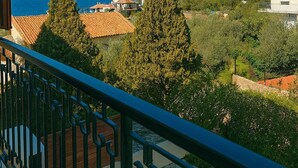 A balcony with a view of the sea, trees, and buildings.