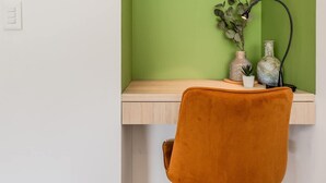 A workspace with a wooden desk, a green wall, a brown chair, and a small plant. - NOK Perfect Loft in Chic (Bogotá)