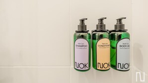 Three bottles of NUK hair and body care products on a white tiled wall. - NOK Perfect Loft in Chic (Bogotá)