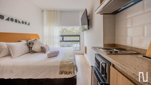 A modern hotel room with a bed, a kitchen area, and a large window. - NOK Perfect Loft in Chic (Bogotá)