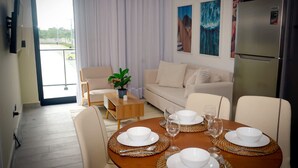 A dining area with a wooden table set for four, a sofa, and a refrigerator.