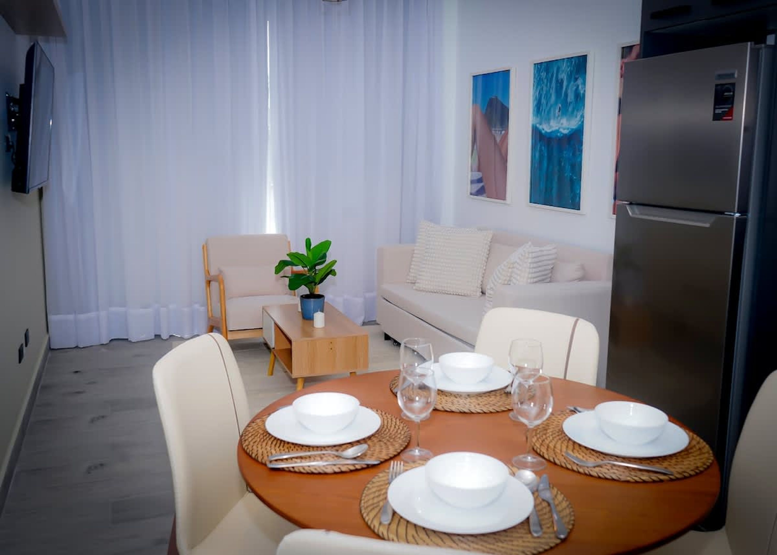 A dining area with a round table set for four, a sofa, a coffee table, and a refrigerator.