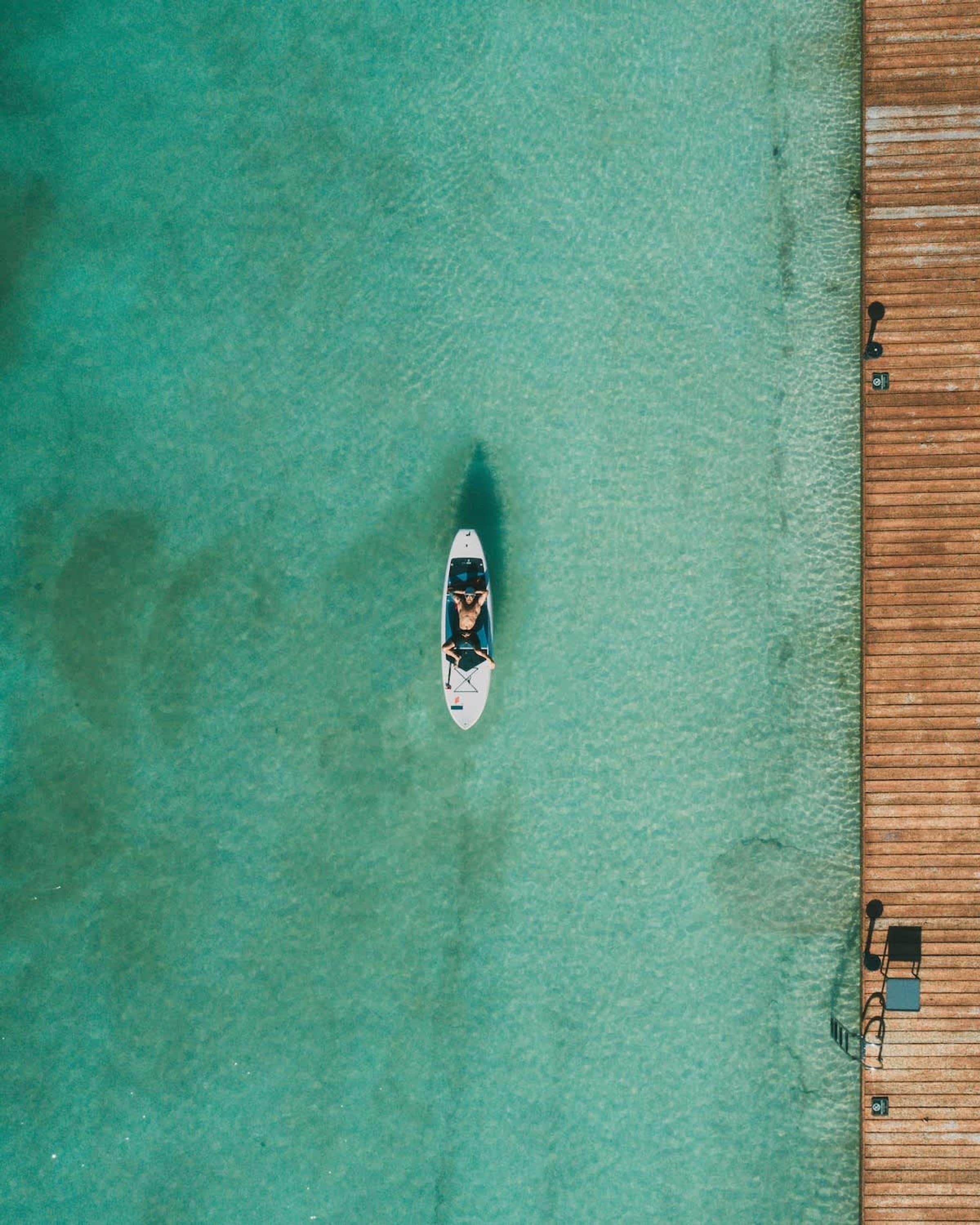 Luftaufnahme eines Strandes mit einer Holzsteg und einem Boot im Wasser.