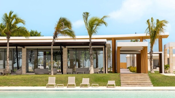 Ein modernes Resort mit Pool, Liegestühlen und Palmen.