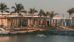 Ein modernes Hotel mit Pool, Palmen und blauem Himmel.
