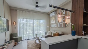 Ein modernes Wohnzimmer mit großem Fenster, einer Couch, einem Couchtisch und einem Fernseher.