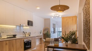 Una cocina moderna con armarios de madera, horno empotrado y comedor con mesa y banco de madera.