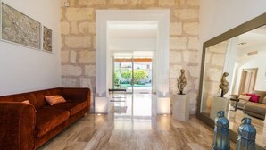 A spacious living area with a stone wall, a red velvet sofa, and a large mirror reflecting the room. - Bouganvilla House FOR 6 PERSONS (Ariany)