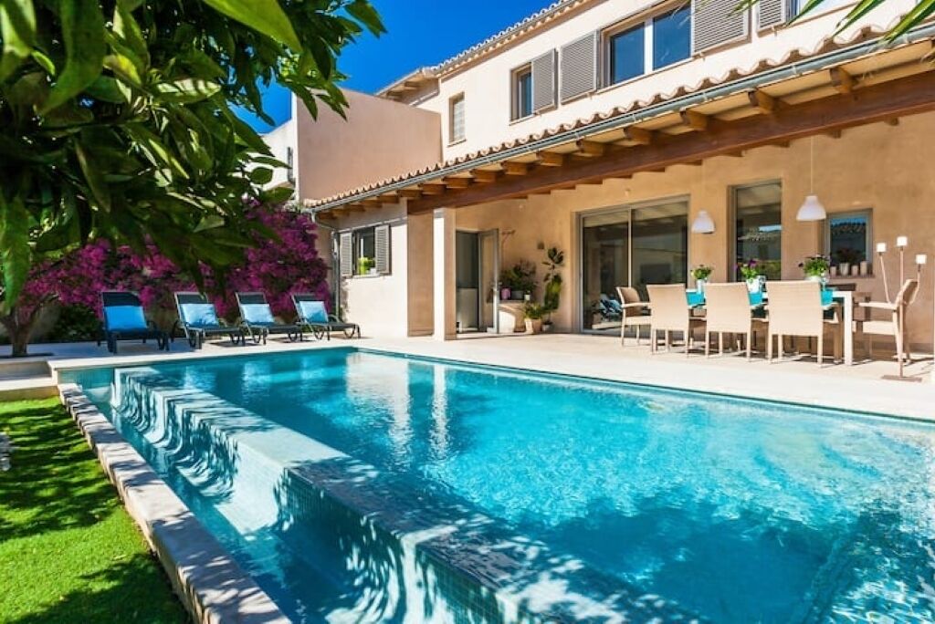 A swimming pool with lounge chairs and a patio area with potted plants.