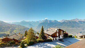 A mountain lodge with a modern design, featuring a spacious patio area and a view of the surrounding mountains.