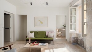 A modern living room with a green sofa, a coffee table with flowers, and a map on the wall.
