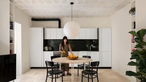A modern kitchen with white cabinets, a round dining table, and black chairs.