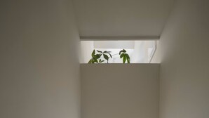 A narrow staircase leading to a landing with a view of a snowy outdoor scene.